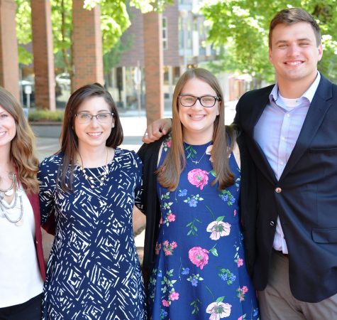 Four young people smiles for the camera with their arms around one another.