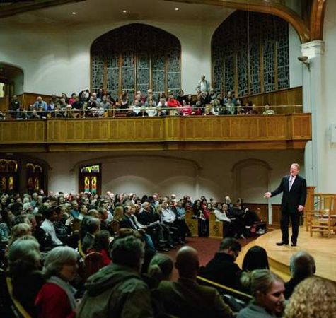 A man in a dark suit on stage at Seattle Arts & Lectures